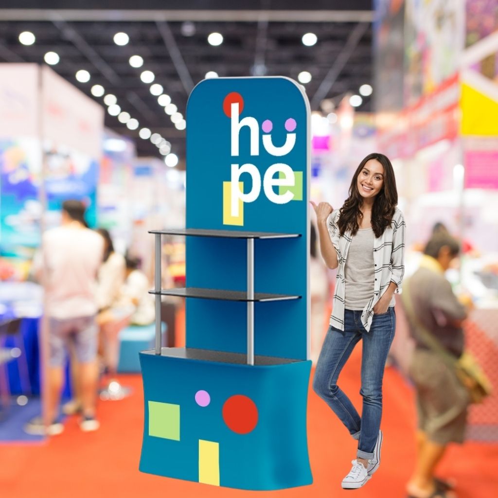 Tabletop tower display with shelves holding product samples at an exhibition